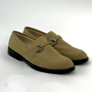 A slip-on shoe with a gold buckle